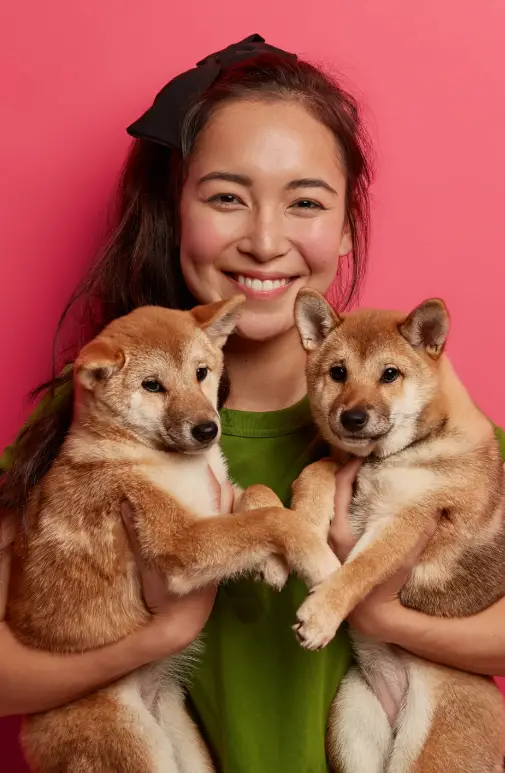 happy brunette girl adopts two puppies from shelter happy have new friends holds pets being dog lover going walk animal owner suggests adopt pet smiles gladf