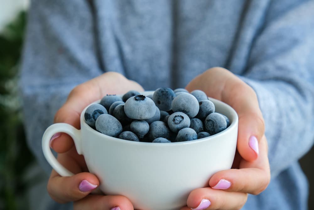 Woman holding mug of blueberries